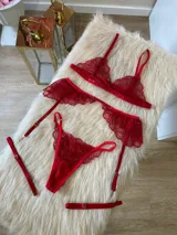 Conjunto de lencería compuesto por bralette de encaje con breteles regulables, tanga regulable y portaligas con volados en las caderas.