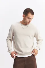 Sweater de algodón con textura acanalada, cuello redondo, mangas largas con hombros caídos y calce relajado. Presenta un logo bordado sutil en el pecho.