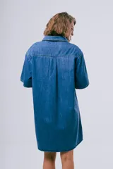 Vestido corto de denim azul oscuro, con cuello camisero, mangas cortas, cierre frontal con botones, bolsillo aplicado en el pecho y calce holgado.