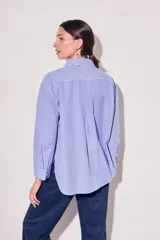 Camisa celeste con rayas verticales blancas, de corte clásico, con cuello camisero y mangas largas.
