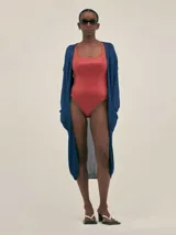 Cardigan largo azul tejido en jersey con lurex, con bolsillos en el frente y detalle en cobre con logo.