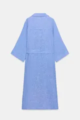 Vestido midi de cuello solapa con escote en pico y mangas tres cuartos ajustables con trabilla. Cuenta con bolsillos delanteros de plastrón, bolsillos laterales ocultos en costura, cierre frontal con botones y cinturón ajustable del mismo tejido con hebilla metálica circular.