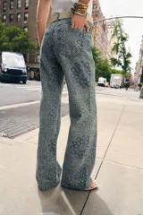 Jeans de tiro alto con corte flare y diseño de tejido jacquard con patrón floral. Presenta cinco bolsillos, trabillas en la cintura y cierre frontal con cremallera y botón.