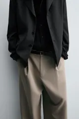 Pantalón de corte relajado en color verde militar, con diseño de pliegues frontales, bolsillos laterales y cierre de cremallera con botón.