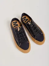 Championes de lona negra con plataforma y puntera de goma marrón, cordones negros y costuras en contraste.