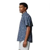 Camisa de manga corta Columbia, diseñada para pesca, con estampado de peces y elementos náuticos. Presenta cuello abotonado, cierre frontal con botones, múltiples bolsillos en el pecho y ventilación trasera forrada en malla.
