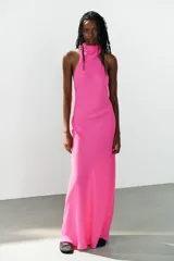 Vestido largo fucsia de cuello halter, espalda descubierta y cierre lateral con cremallera oculta en costura.