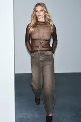 Jeans de tiro medio con diseño de pierna curva tipo barrel, confeccionados en denim con efecto lavado. Presentan cintura con trabillas, cierre frontal con cremallera y botón, y cinco bolsillos clásicos.