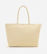 Cartera amplia confeccionada en fibra de papel, de color beige, con asas de hombro, cierre superior y detalle metálico dorado claro en el frente.