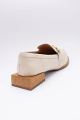 Mocasines de cuero en tono bronce metalizado, con detalle de aplique metálico dorado en el empeine y taco cuadrado bajo de madera.