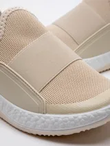 Zapatilla beige de tela tejida, con piezas de goma en los laterales y pieza elástica sobre el empeine. Plataforma texturada de 4 cm de alto.