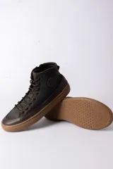 Championes de caña alta confeccionados en cuero marrón oscuro, con cordones al tono y suela de goma color caramelo.