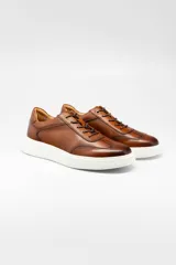 Champion de cuero color marrón con suela de goma blanca, diseño de cordones y costuras reforzadas.