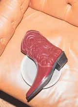 Bota corta tipo texana en cuero acharolado con punta afinada y taco bajo.