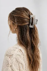 Pinza de pelo bordó de diseño rectangular con abertura central, ideal para recoger el cabello.