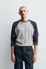Camiseta de corte relajado con diseño color block, cuerpo en gris melange y mangas largas raglán en color azul marino. Presenta cuello redondo al tono de las mangas y bajo con acabado irregular.
