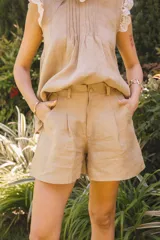 Short amplio color beige, con pinzas frontales, bolsillos laterales y cierre frontal con botón forrado.