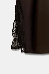 Top sin mangas color marrón oscuro con cuello drapeado y abertura en la espalda con botón. Presenta detalles de encaje a tono en las aberturas laterales.