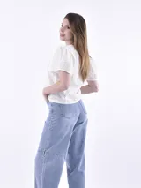 Blusa color beige con pequeños calados, mangas cortas abullonadas y escote redondo.