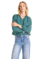 Blusa de satén color verde petróleo, con escote en V y cuello decorado con mostacillas bordadas. Presenta mangas largas con puños elásticos y ruedo también elastizado, brindando un ajuste cómodo y holgado.