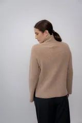 Polera gris de tejido de punto grueso, con cuello alto y mangas largas.