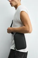 Bandolera negra con acabado texturizado, compartimento principal con cierre de cremallera, bolsillo interior plano, bolsillo frontal plano y asa de hombro ajustable y extraíble.