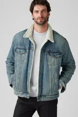 Campera de jean celeste Levi's modelo Type 3 Sherpa con cuello de corderito color crema, bolsillos frontales con solapa y cierre de botones metálicos.