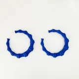 Par de aros tipo argolla de resina color lila, con diseño que imita cañas de bambú.