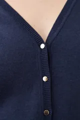 Cardigan de punto negro con escote en V, cierre frontal con botones metálicos dorados y mangas largas con puños ajustados que incluyen detalles de botones decorativos.