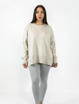 Buzo de tejido de punto en color beige, con cuello redondo, manga larga y diseño holgado. Presenta una costura vertical decorativa en el frente y terminaciones en rib en puños y ruedo.