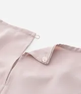 Blusa de crepé color rosa pálido, con cuello redondo, mangas cortas con volados, lazo en la cintura y botón en la espalda.