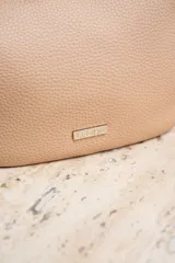 Cartera de mano color arena, con cierre superior y logo de la marca en el frente.