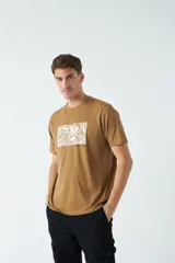 Remera de hombre color marrón, manga corta, con escote redondo y un estampado rectangular con diseño botánico en color blanco.