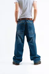 Pantalón de jean azul oscuro con efecto desgastado, corte mega baggy de tiro alto y pierna ancha. Presenta cinco bolsillos y botones personalizados.