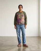 Campera bomber con diseño de paneles combinados: mangas y espalda en color verde oliva acolchado, y frente con paneles laterales estampados en tonos tierra y violeta. Presenta cuello, puños y ruedo en tejido de punto acanalado color marrón, con cierre frontal completo.