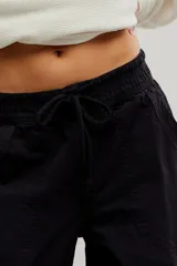 Pantalón de denim blanco de tiro medio con cintura elástica ajustable mediante cordón, bolsillos plaqué delanteros y diseño de corte amplio y holgado.