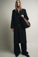 Bolso tipo saca confeccionado en piel, con diseño de doble compartimento interior, asa de hombro y bolsillo interno con cierre de cremallera.