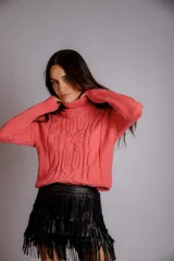 Suéter tejido de punto trenzado color salmón, con cuello alto y mangas largas. Corte ajustado al cuerpo.