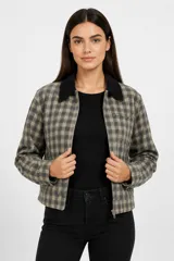 Campera de corte recto con estampado a cuadros en tonos gris y beige, cuello camisero en color negro, cierre frontal con cremallera y bolsillos laterales.