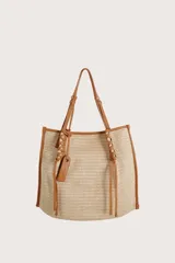 Bolsa tipo tote de textura tejida en color natural, con detalles de ribetes, asas y cordones decorativos en cuero sintético color suela.