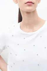 Remera blanca de algodón con cuello redondo y apliques de strass plateados.