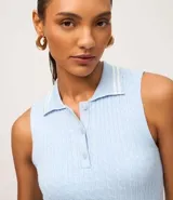 Top sin mangas de punto color celeste claro, con cuello polo ribeteado con dos líneas blancas y cierre frontal de tres botones. El tejido presenta un patrón de trenzas verticales.
