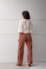 Pantalón de jean color ladrillo, de corte recto y tiro alto, con aberturas laterales en el ruedo y detalle de botones.