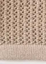 Cardigan de punto calado color beige, de diseño recto, cuello redondo, manga corta y cierre frontal con botones.