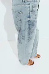 Jeans Z1975 de tiro medio y pernera recta con diseño de cinco bolsillos, cierre frontal con cremallera y botón, y delicado estampado floral en tonos azules.
