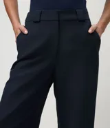 Pantalón de sastrería corte recto, color marrón, con cintura de tiro medio, trabillas largas y bolsillos traseros.