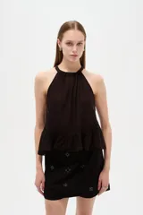 Top blanco de algodón con cuello halter, diseño holgado y detalle de encaje en el borde inferior.