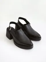 Zapato tipo slingback color negro, con plataforma y taco cuadrado. Presenta una puntera cuadrada y cierre con hebilla metálica en la tira trasera.