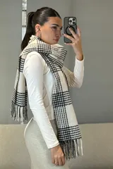 Bufanda rectangular con diseño de cuadros escoceses en blanco y negro, con flecos en los extremos.