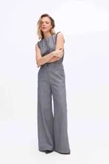 Pantalón de pierna amplia y tiro alto, confeccionado en tejido a rayas con una mezcla de algodón, poliéster y lino. Presenta un diseño de corte sastrero con bolsillos laterales y trabillas para cinturón.